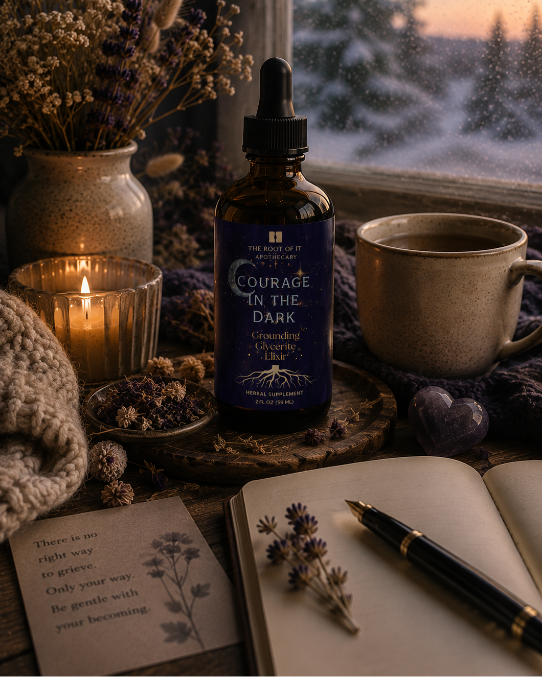 A dark amber dropper bottle labeled 'Courage in the Dark' stands on a wooden surface by a window, surrounded by dried flowers in a vase, a lit candle, a ceramic mug, a notebook, and a pen. A snowy outdoor scene is visible in the background.