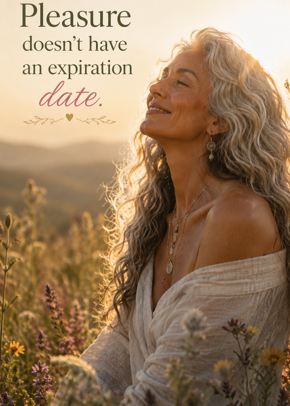 A woman with long wavy gray hair sits in a sunlit field of wildflowers, wearing an off-the-shoulder cream top. Text on the left reads, 'Pleasure doesn't have an expiration date.