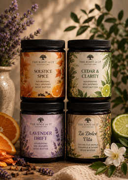 Four jars of body butter arranged in a 2x2 grid on a rustic wooden surface with botanical props. The products are from The Root of It Apothecary and include Solstice Spice, Cedar & Clarity, Lavender Drift, and La Dolce Vita.